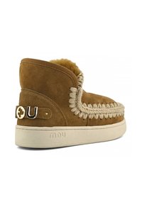 Stivale alla caviglia in suede tan con fodera in pelliccia, cuciture decorative e un accento con logo. Presenta una suola in gomma crema per un contrasto.