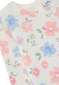 Pull en tricot crème avec un motif floral pastel, mettant en avant des fleurs roses, bleues et vertes. Col rond et détails côtelés.