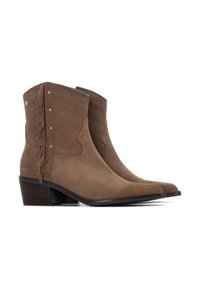 Botas de tobillo de ante color crema con punta afilada, acabado texturizado, detalles de flecos en los laterales y un tacón bajo y apilado.