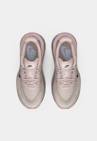 Light pink athletic shoes with mesh upper and textured patterns. Features a blue logo, lace-up design, and cushioned sole.