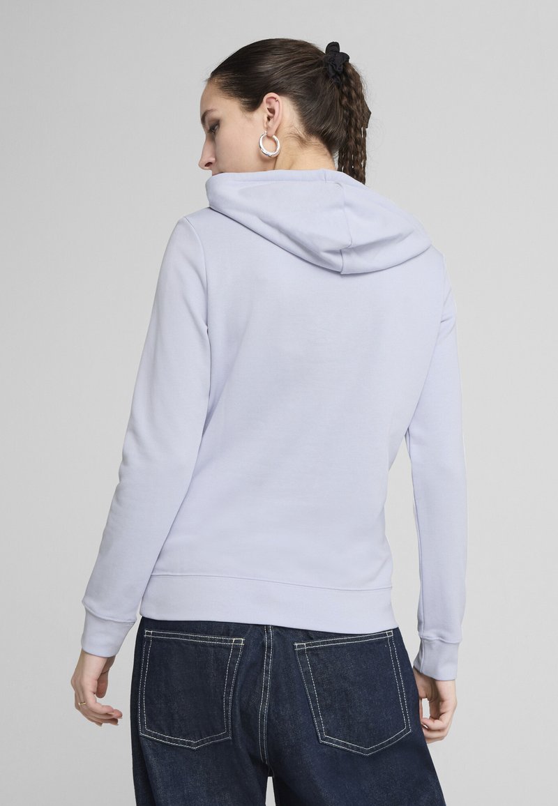 Fioletowa bluza z kapturem i sznurkiem, z ribbowymi mankietami i dół. W połączeniu z ciemnoniebieskimi dżinsami denimowymi z tylnymi kieszeniami i detalami w przeszyciach.