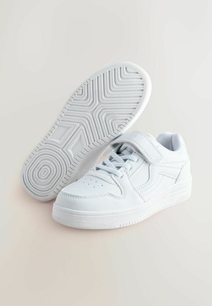 Bílé tenisky s hladkým koženým povrchem, zavazováním na tkaničky a nastavitelným páskem, s texturovanou gumovou podrážkou a perforovaným designem na špičce.