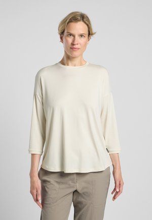 Hellbeige, langärmliges Oberteil mit lockerer Passform und rundem Ausschnitt. Weiche, glatte Textur mit einer schlichten Silhouette. Leichter Stoff ohne sichtbare Muster.