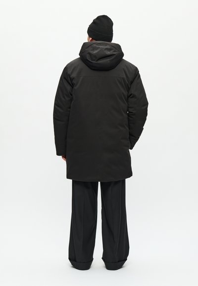 Black padded coat with a hood, featuring a smooth texture and a relaxed fit. Paired with loose black trousers, both offering a minimalist design.