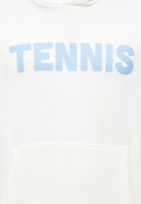 Sweat à capuche blanc avec une poche avant et le mot "TENNIS" imprimé en grandes lettres bleu clair sur la poitrine.