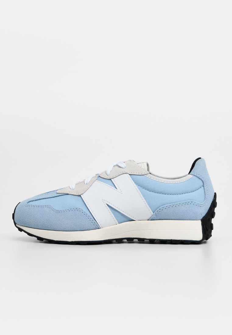 Zapatilla de running azul claro con materiales de ante y malla, que presenta un gran logotipo blanco de 'N', detalles en gris y una suela de goma negra.