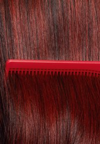 Röd kam placerad på mörkröda och svarta hårstrån, med fina tänder och en slät plaststruktur. Framträdande glansig finish.