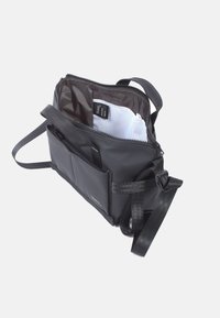 Borsa nera con tracolla regolabile, apertura con zip, molteplici scomparti, texture liscia e design minimalista. L'interno include etichette.