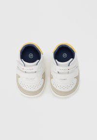 Λευκά και μπεζ αθλητικά παπούτσια για νήπια με λουράκια με βέλκρο, διάτρητο σχέδιο στη μύτη, ναυτικό εσωτερικό και κίτρινες λεπτομέρειες στη φτέρνα. Μέγεθος 17.