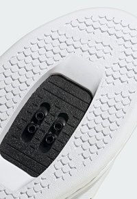 Bílá podešev boty s kruhovými vzory, texturovanou černou částí s drážkami a otvory pro šněrování uprostřed.