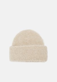 Căciulă din tricot bej cu un material moale și texturat. Are un tiv rulat și un vârf rotund, asigurând o potrivire strânsă.