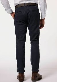 Chino navy con vestibilità slim, con orli arrotolati, tasche laterali e posteriori, e una texture di tessuto liscia. Abbinati a scarpe in pelle marroni.