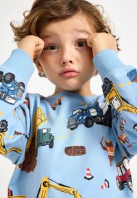 Jasnoniebieska bluza z kolorowymi ilustracjami pojazdów budowlanych, pachołków i pracowników; wykonana z miękkiego materiału zapewniającego wygodne dopasowanie.