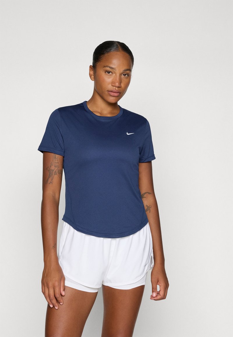 Granatowa, sportowa koszulka z krótkim rękawem wykonana z tkaniny odprowadzającej wilgoć, z okrągłym dekoltem i subtelnym logo Nike, w zestawie z białymi szortami.
