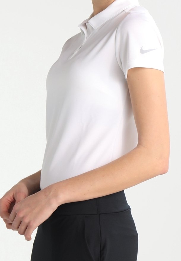 Vit polo skjorta med knäppkrage, korta ärmar och Nike-logotyp på vänster ärm. Tyget verkar slätt och lätt.