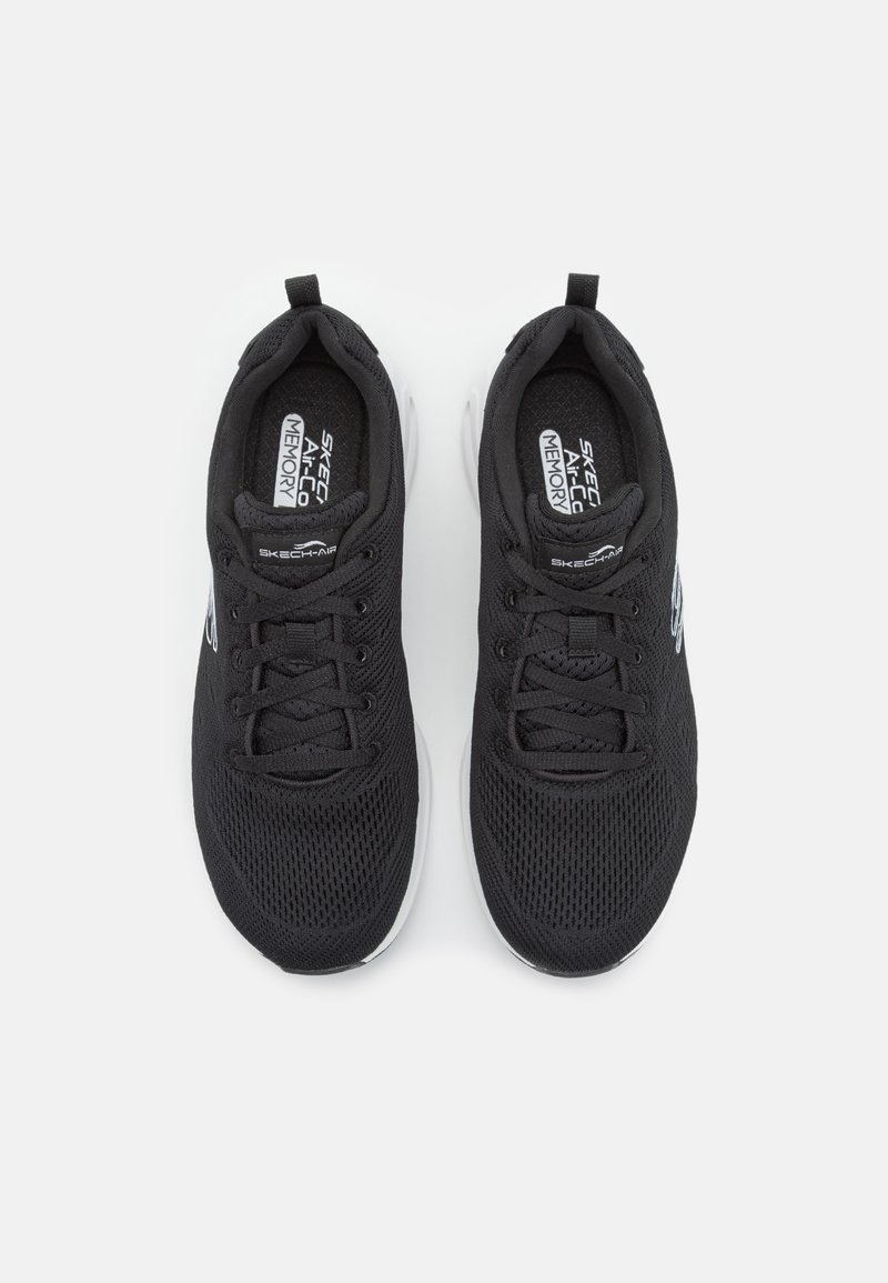 Svarta mesh-sportskor med en texturerad ovansida, rund tå och vit gummisula. Har snörning och varumärke på sidan och tungan.