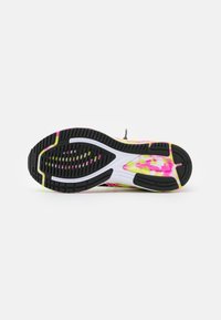 Semelle de chaussure de course avec une base en caoutchouc noir agrémentée d'éclaboussures colorées de rose, de jaune et de blanc, texturée pour l'adhérence et la flexibilité.