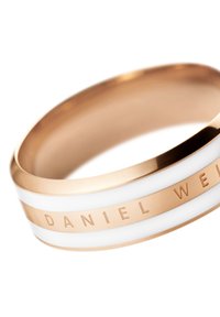 Rožnato zlato prstan z belimi emajliranimi črtami, ki vključuje graviran tekst "DANIEL WELLINGTON" na gladki, zaobljeni zasnovi.