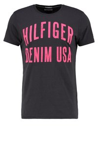 Černé bavlněné tričko s velkým růžovým nápisem "HILFIGER DENIM USA." Klasický kulatý výstřih a krátké rukávy. Hladká textura.