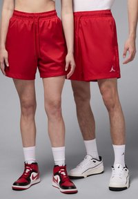 Rote Sportshorts aus glattem Material mit elastischem Bund und Kordelzug. Mit einem kleinen weißen Logo am Saum.