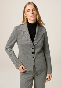 Zwart-wit houndstooth-patroon blazer met een aansluitend ontwerp, notch revers, vier zwarte knopen en gestructureerde schouders.