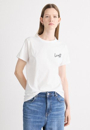 Bela bombažna majica s kratkimi rokavi in okroglim izrezom, z natisnjeno črno srce in grafiko "Love" na levi prsni strani.