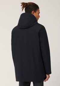 Giacca impermeabile blu navy con vestibilità comoda, dotata di un ampio cappuccio, maniche lunghe e orlo dritto. Texture liscia e design minimalista.