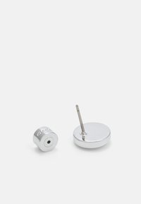 Pendientes de plata con un disco redondo y forma cilíndrica, superficie lisa y un punto para el piercing. Diseño minimalista y acabado brillante.