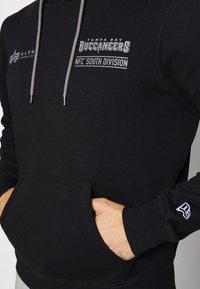 Felpa nera con tasca frontale, coulisse grigia e grafiche dei Tampa Bay Buccaneers sul petto. Tessuto morbido e design casual.