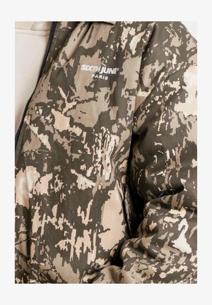 Chaqueta de camuflaje con una mezcla de colores verde, beige y marrón, con cierre de cremallera y un logo "SIXTH JUNE PARIS" en el pecho.