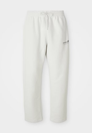 Šviesiai pilki sportiniai džinsai, pagaminti iš minkštos medžiagos, su elastingu juosmeniu ir raišteliu bei mažyčiu logotipo elementu ant kairiojo šlaunies.