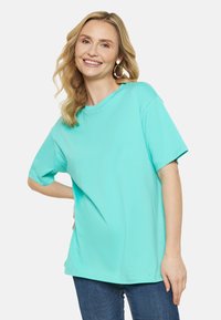 Turkosa överdimensionerad t-shirt i bomull, med rund hals och korta �ärmar. Slät textur, minimal sömdetaljering.