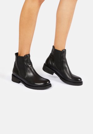 Botas de tobillo de cuero negro con paneles elásticos laterales, puntera redondeada y tacón bajo apilado. La suela tiene un acabado texturizado para un mejor agarre.