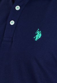 Navy polo shirt made of cotton, featuring a three-button placket and a light blue embroidered logo of a polo player on the left chest.