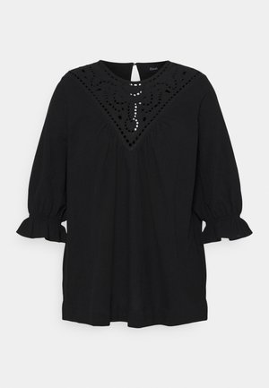 Musta pusero, jossa on 3/4-pitsihihat, kirjailtu pääntie ja leikatut yksityiskohdat. Pehmeä kangas, rento leikkaus ja röyhelöidyt hihansuut.