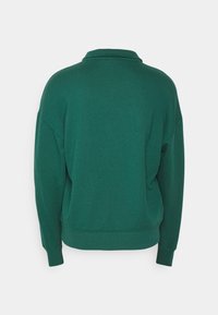 Sweat-shirt vert foncé à manches longues avec col, poignets côtelés et taille côtelée, présenté de dos sur un fond uni.