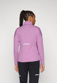 Lange mouwen, slim fit jas in lichtpaars, met een hoge kraag, gestructureerde stof en een reflecterende accent op de rug met een geometrisch patroon.