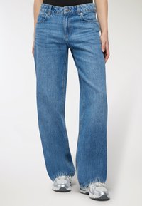 Jasnoniebieskie dżinsy w stylu wide-leg wykonane z denimu z delikatnym wypłukanym wykończeniem, z pięcioma kieszeniami, szlufkami na pasek oraz zamkiem błyskawicznym i zapięciem na guzik.