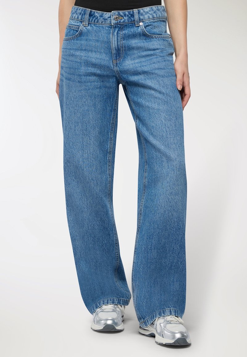 Jasnoniebieskie dżinsy w stylu wide-leg wykonane z denimu z delikatnym wypłukanym wykończeniem, z pięcioma kieszeniami, szlufkami na pasek oraz zamkiem błyskawicznym i zapięciem na guzik.