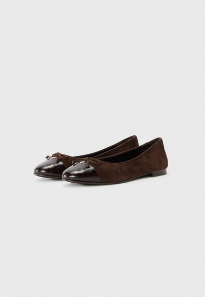 Chaussons en suede marron avec un bout en vernis à motif crocodile et des nœuds sur le devant. Semelle plate avec un petit talon. Design simple et élégant.