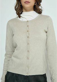 Cardigan beige chiaro con scollatura rotonda, orlo a costine e chiusura frontale con bottoni piccoli e rotondi lungo una patta.