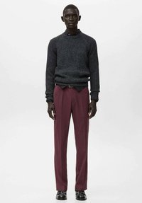 Jersey gris de punto con textura acanalada, combinado con pantalones burdeos de corte entallado. La modelo lleva zapatos negros y posa sobre un fondo blanco.