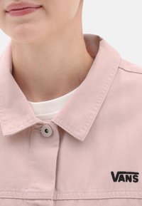 Jasnoróżowa koszula dżinsowa z odznaczającym się kołnierzem i szarym guzikiem. Posiada haftowane czarne logo "VANS" w okolicy kieszeni na piersi.