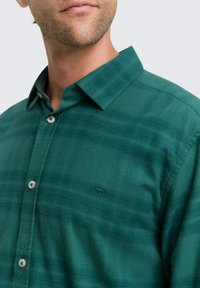 Groene geruite shirt van gestructureerde stof met een button-down kraag, met contrasterende knopen en een logo op de borst.