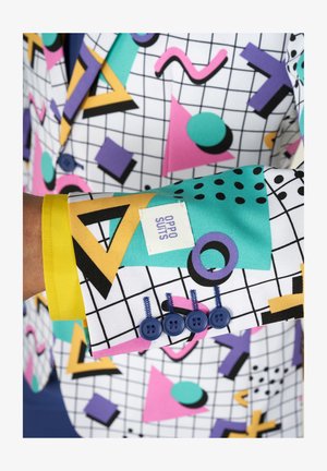 Kolorowa marynarka w kratę z geometrycznymi kształtami w odcieniach różu, zieleni, purpury i żółci. Widoczne niebieskie guziki i etykieta marki.