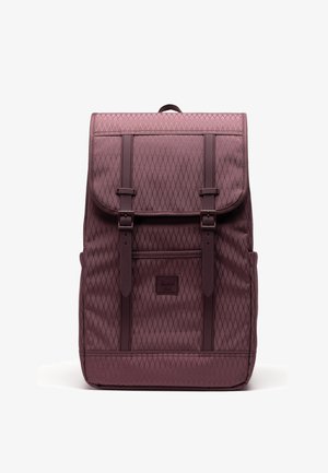 Sac à dos bordeaux à motif losange avec rabat avant, deux sangles verticales à boucle, poignée supérieure et petite poche avant sur fond blanc.