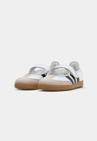 White athletic shoes with a tan suede toe, black stripes, and a Velcro strap, featuring a rubber sole and soft lining.