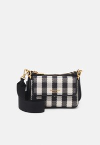 Sac à motifs damiers noir et blanc avec des accessoires en or, fermeture zippée sur le dessus et une bandoulière noire amovible. Présente un tissu texturé et un logo à l'avant.