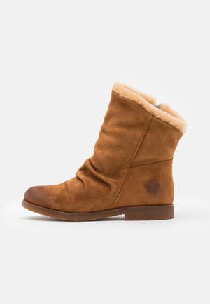 Botte mi-mollet en daim marron avec une semelle plate, une doublure douce en fourrure beige, un léger effet lâche et un logo papillon près du talon.