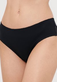 Schwarze Baumwoll-Hipster-Unterwäsche mit glatter Textur, verziert mit einer Spitzenkante entlang des Taillenbandes und der Beinausschnitte.